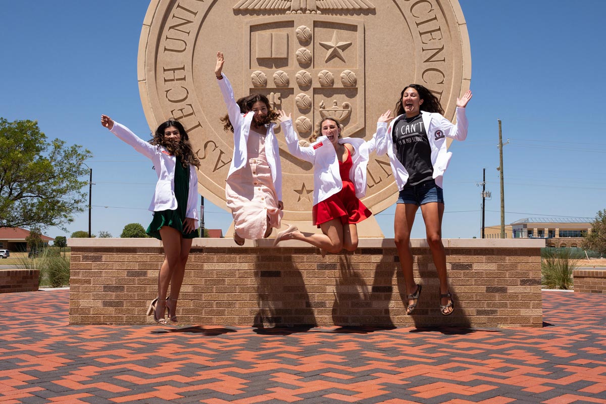 Students jumping in the air for photo at scrub party and white coat ceremonies