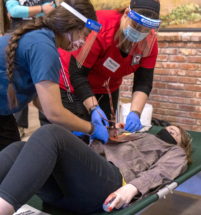 Two nurses working on a patient with a tree limb piercing her abdomen