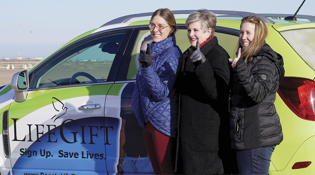 3 women doing #1 hand gestures next to LifeGift car