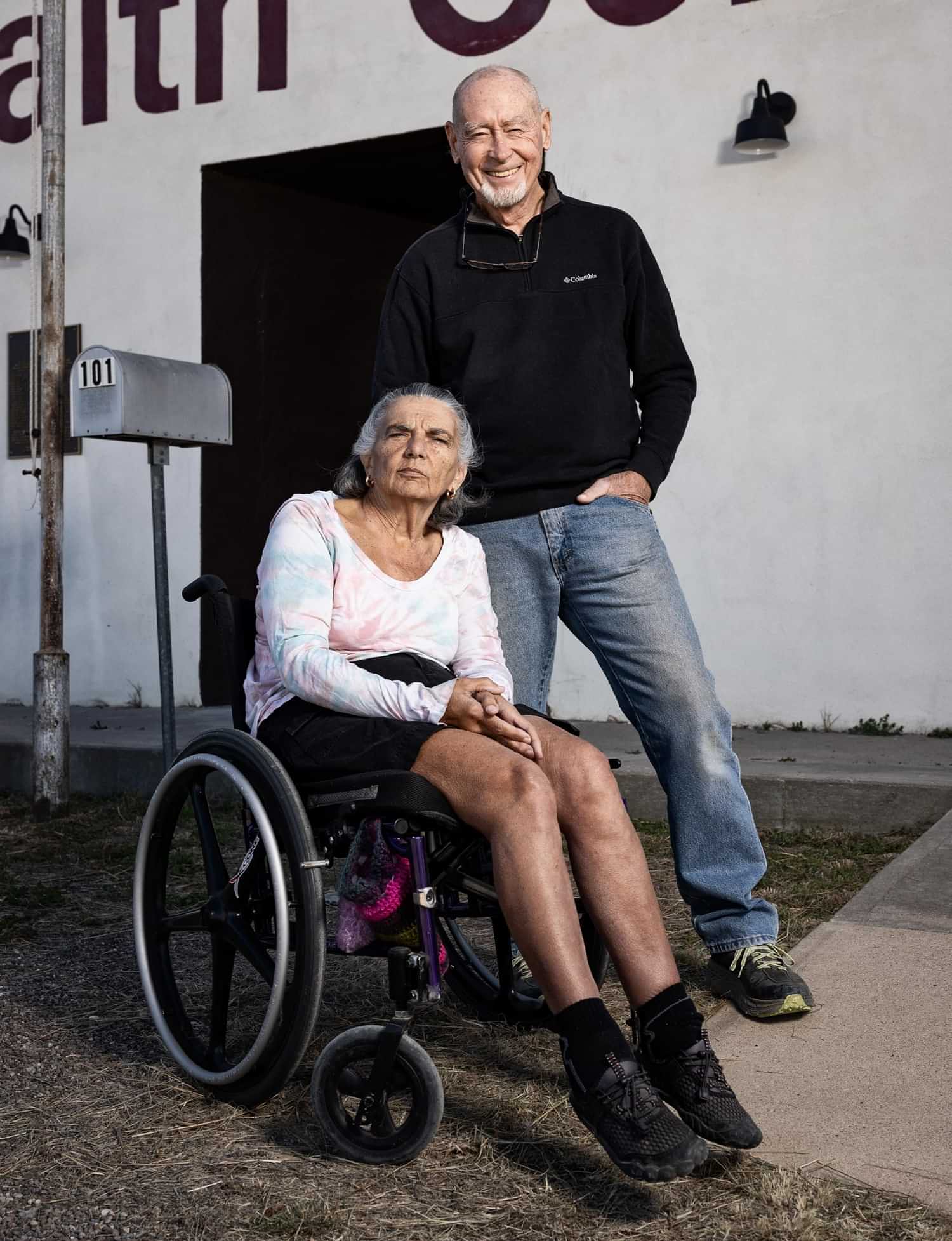 a woman in using a wheelchair next to a man smiling, both in front of the Marathon Health Center