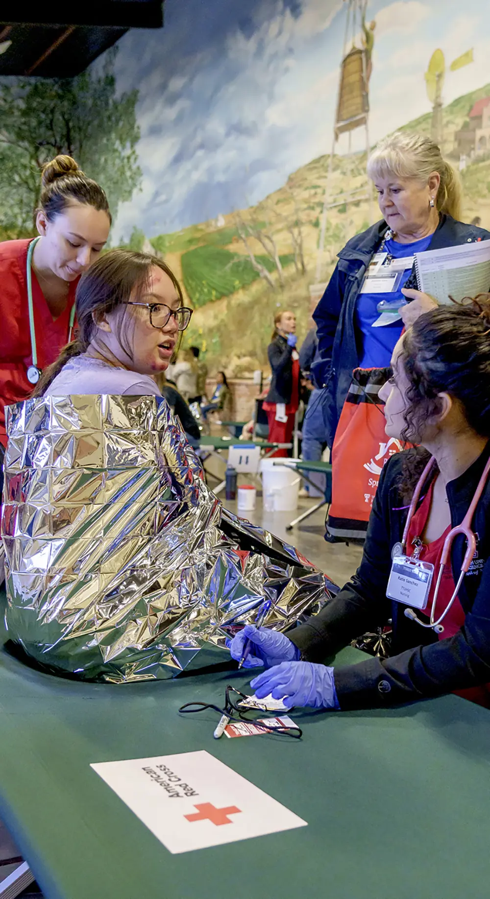 Disaster Day volunteer in foil blanket talking with nurse