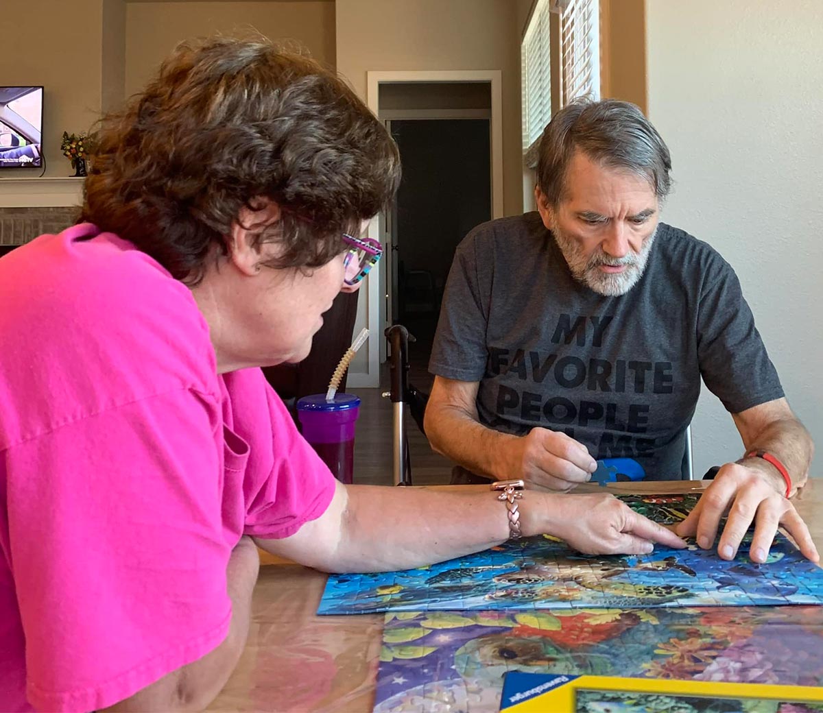 Susan Bergeson and Jim Bertrand seated at a table and working on a jigsaw puzzle