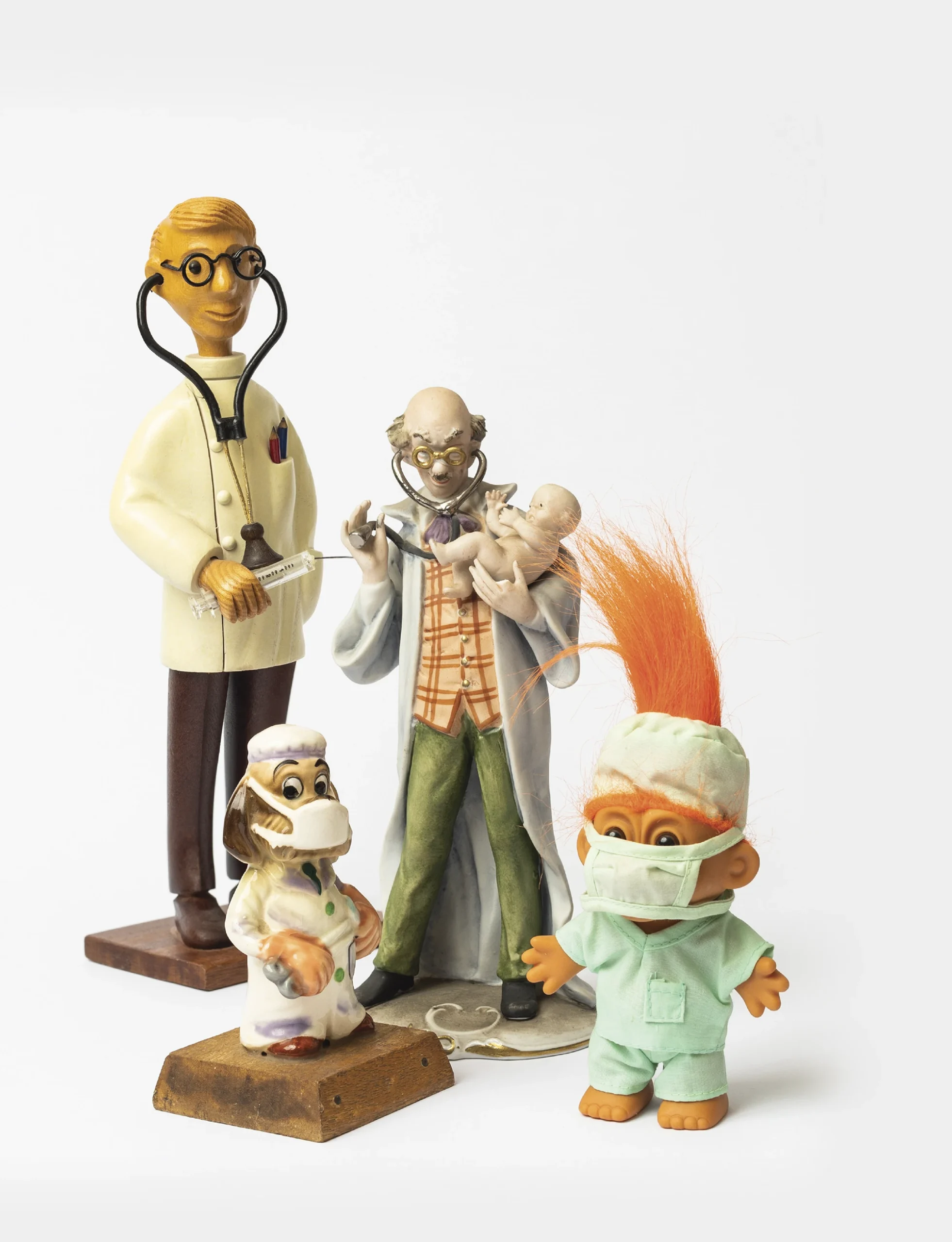 Array of different doctor figurines, like a troll, a dog, a doctor holding a baby and another doctor