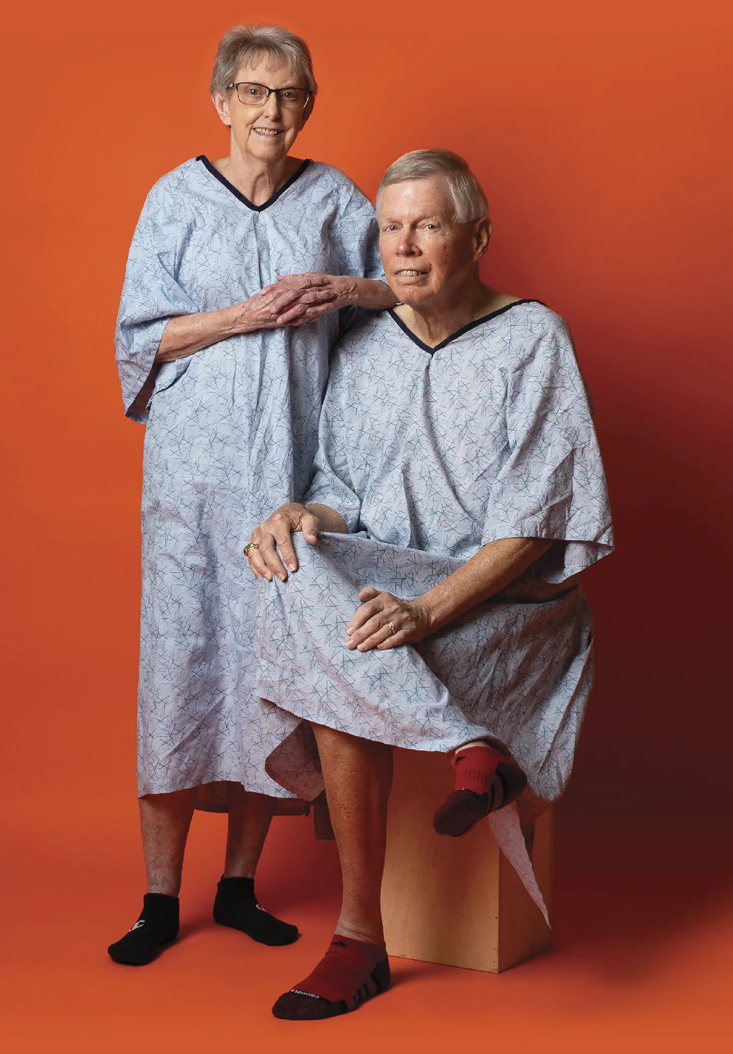 Two older participant patients posing together on an orange background
