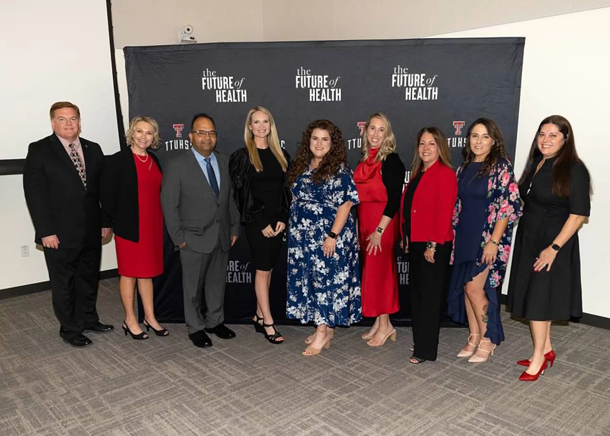 Group of professionally dressed attendees standing in front of a step-and-repeat backdrop reading “The Future of Health” and “TTUHSC,” many holding up a number-one hand gesture during an awards event.