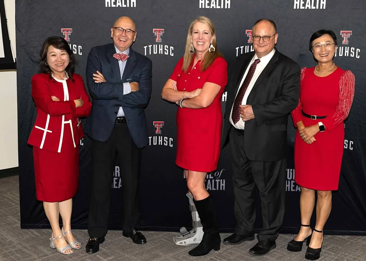 Group portrait of five adults in formal attire posing in front of a TTUHSC-branded “The Future of Health” backdrop, smiling for an event photo.