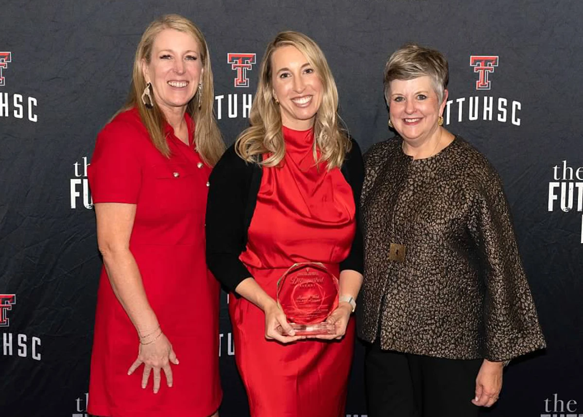 Five adults wearing formal attire pose together in front of a TTUHSC “The Future of Health” backdrop, standing closely and smiling at the camera.