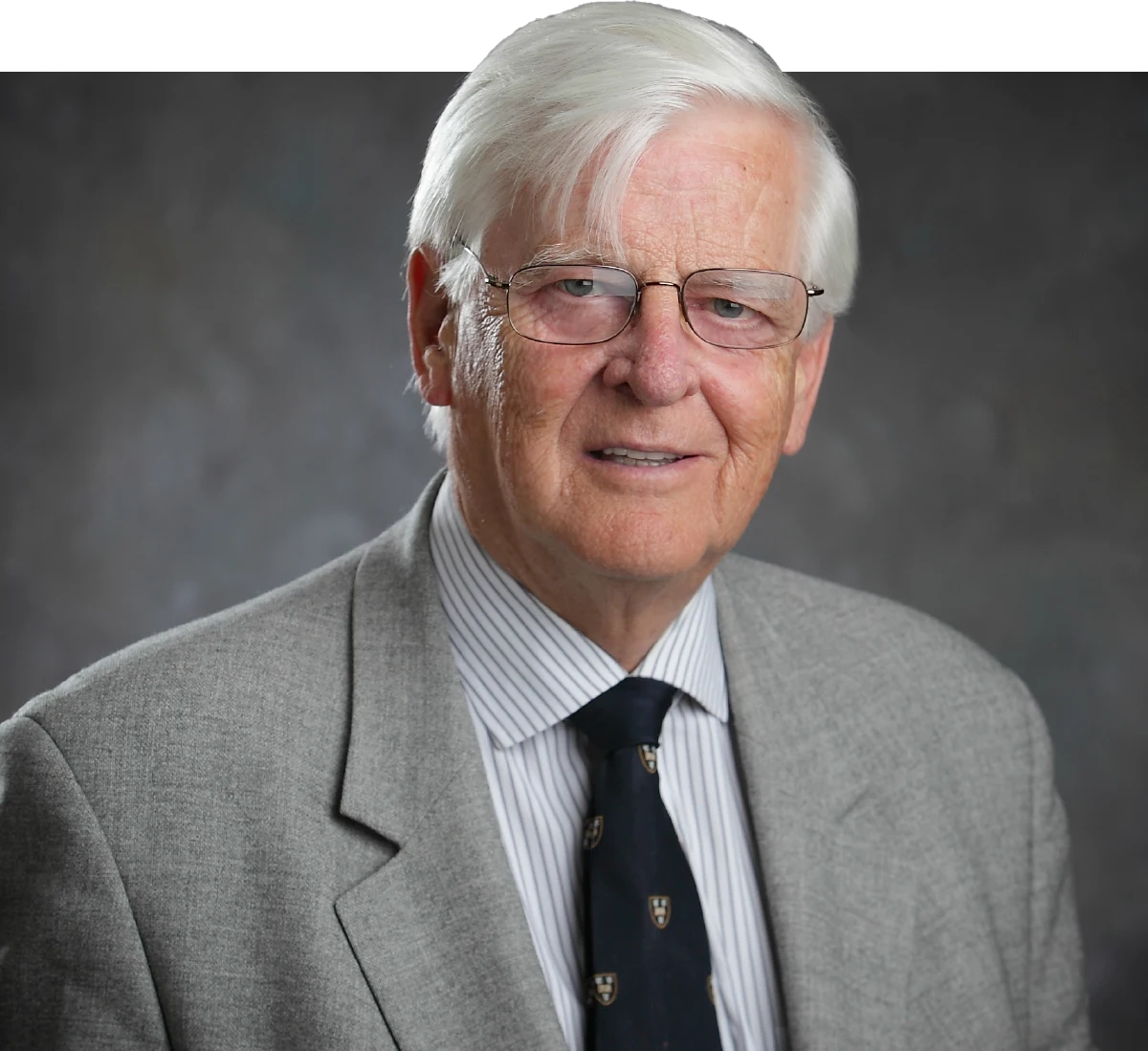 Gabor Racz wearing a gray suit jacket, a striped shirt, and a dark patterned tie.