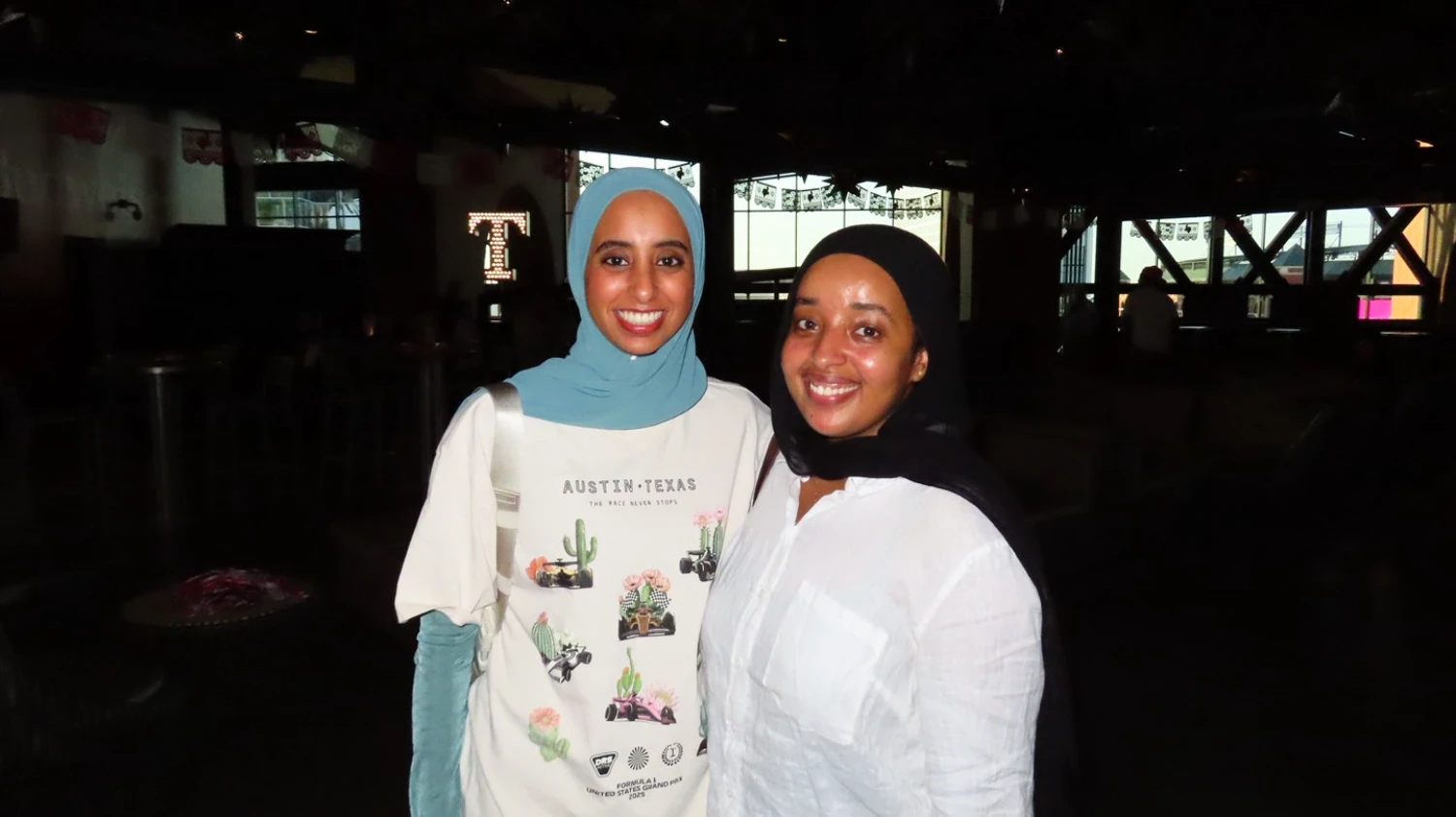 Two women wearing hijabs smile together at a Texas Tech gathering.
