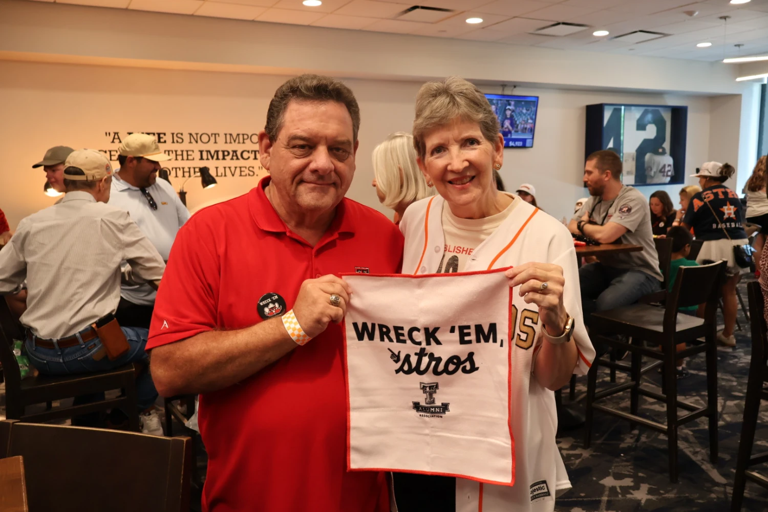 A man and woman hold a Wreck 'Em Astros towel at a Texas Tech alumni gathering.
