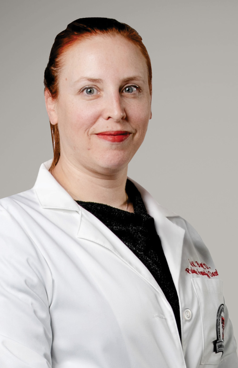 Portrait of Erin Barr smiling while wearing a white lab coat over a black shirt.