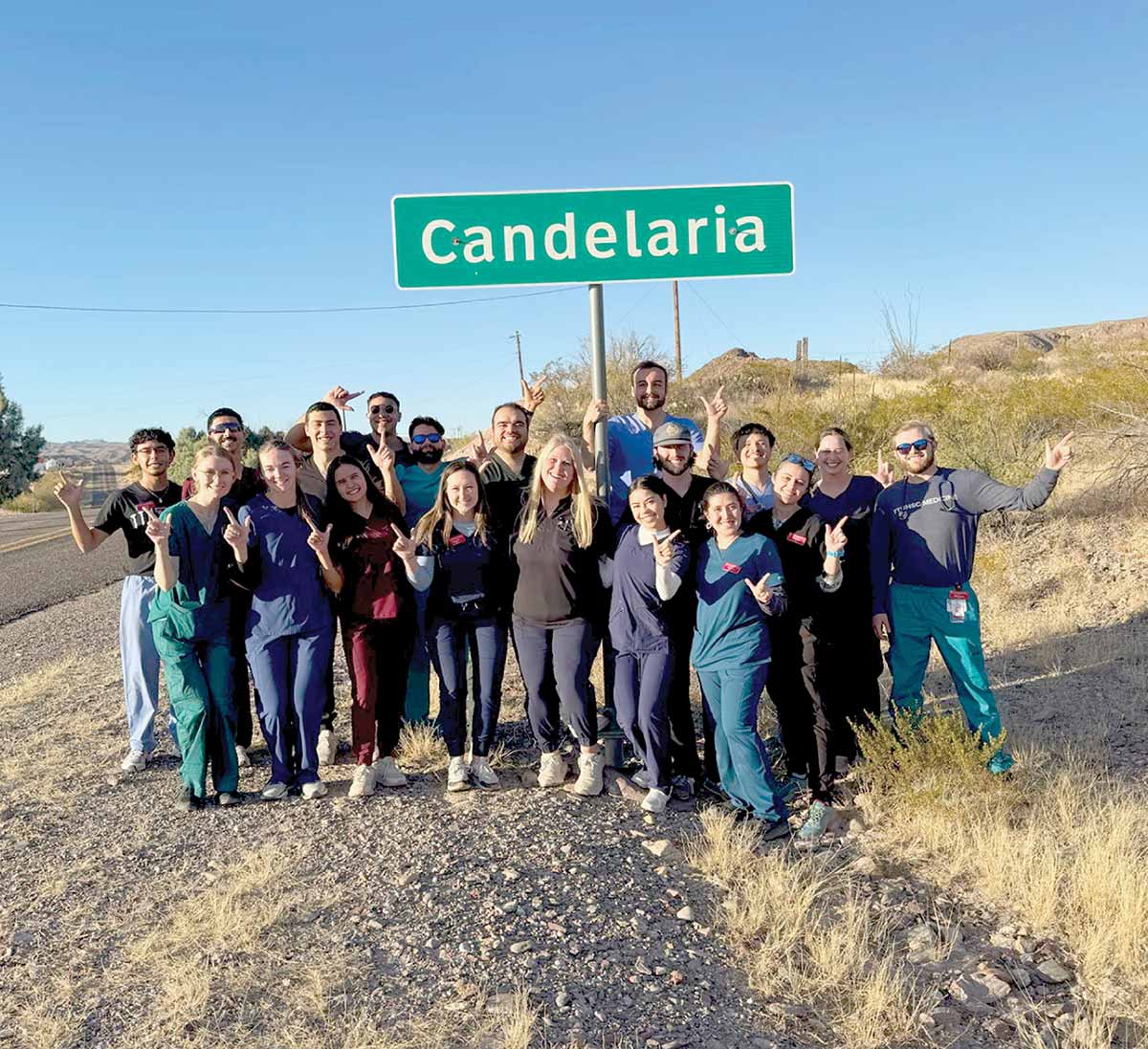 A group of medical students posing together under a "Candelaria" green road sign.