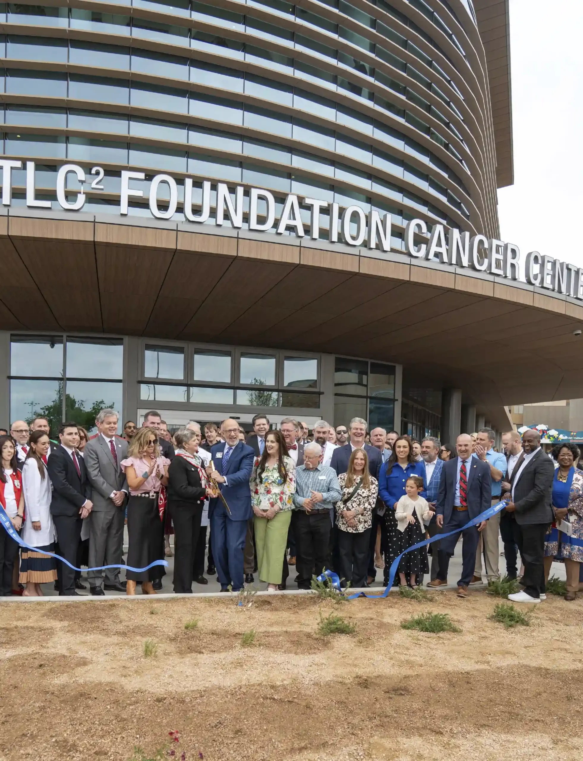 Large crowd cuts a ribbon at the grand opening of the TLC2 Foundation Cancer Center building.