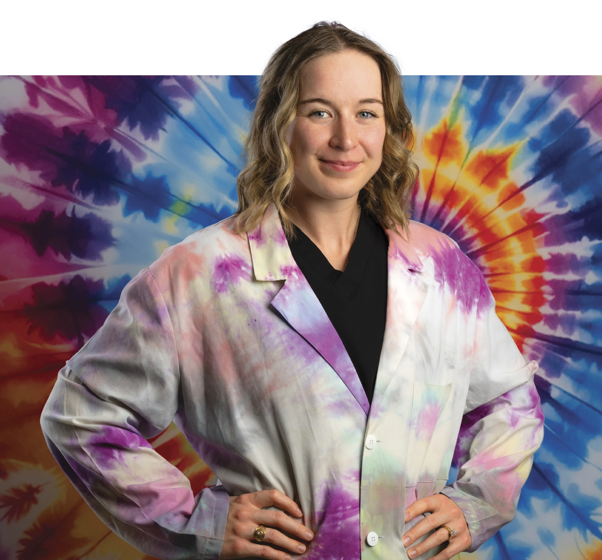 Meg Bowles in tie-dyed lab coat poses in front of a tie-dyed background